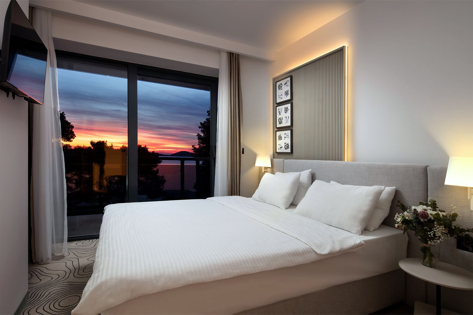 A comfortable hotel bedroom with a sea-view sunset